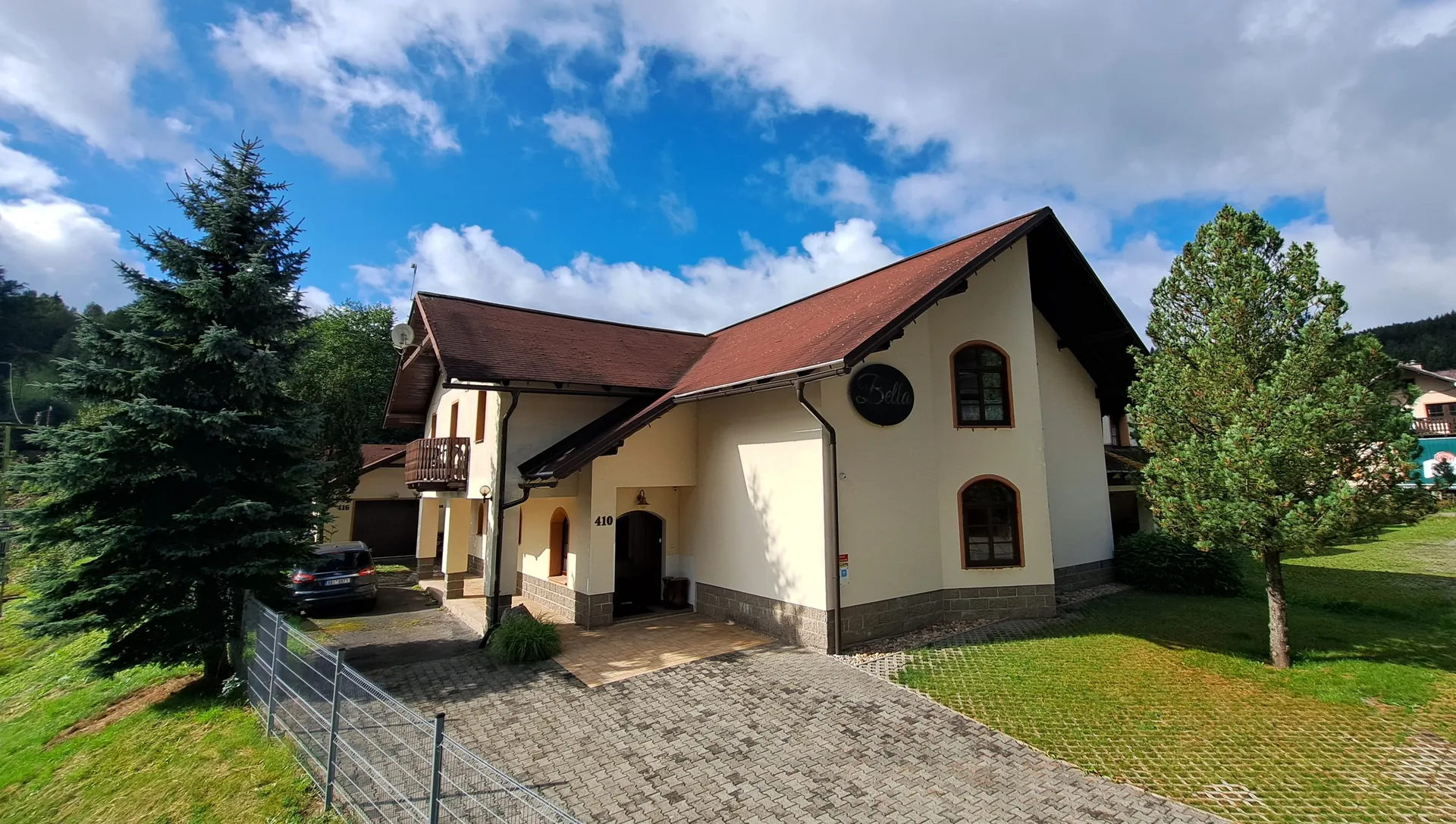 Rodinný penzion Bella v Desné — světlá fasáda, ovál s nápisem Bella a číslo 410 nad vchodem